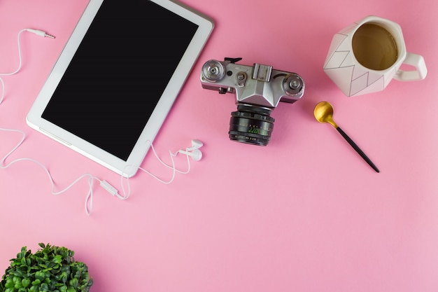 Photo flat lay of laptop, earphones, digital gadget, soft pink background with copy space