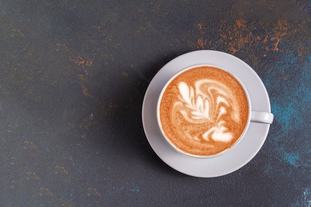 Flat lay latte art coffee with foam in a cup on blue