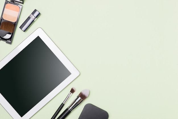 Flat lay of make up cosmetic products with digital tablet on light color background