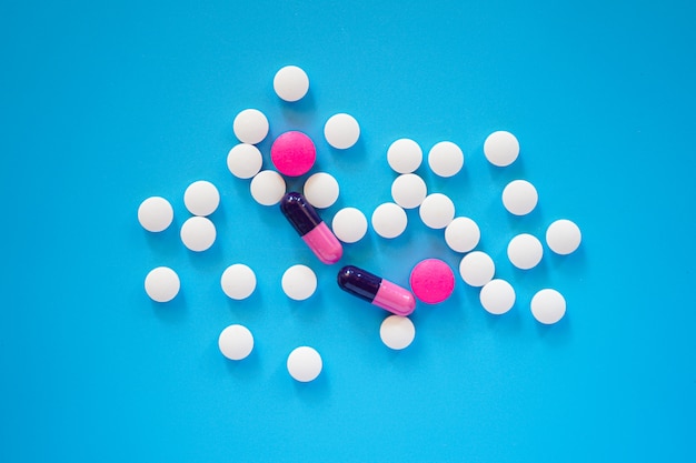 Flat lay of many pills and tablets on blue background