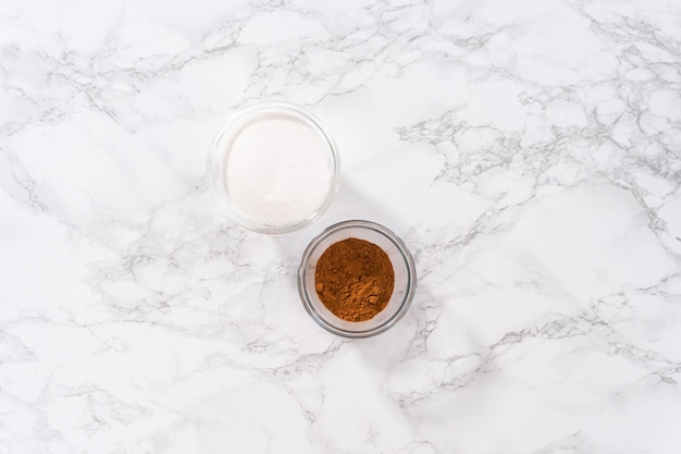 Flat lay. Measured ingredients to prepare homemade cinnamon sugar in small glass bowls.