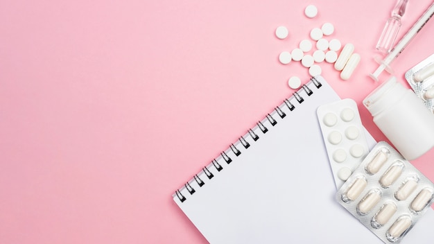 Flat lay medical desk arrangement on pink background with copy space