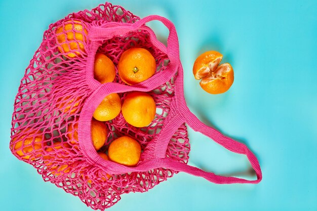 Flat lay Mesh grocery shopping eco friendly tangerine fruits on blue canvas background Zero waste cconcept Local farmers market shopping mall top view copy space Plastic free items