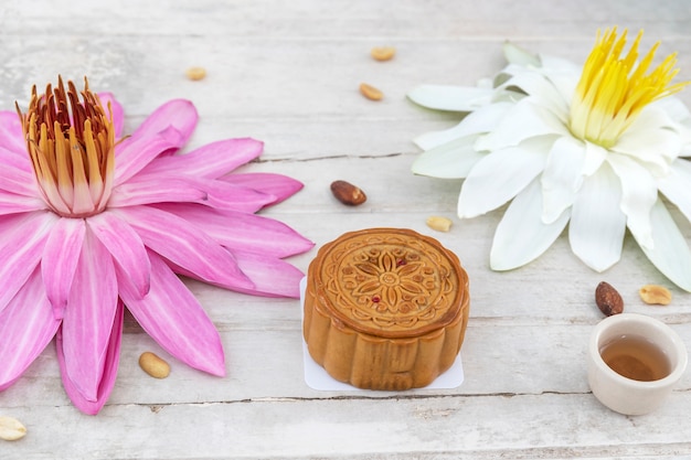 Flat lay of Mid Autumn festival Moon cake on old white table with water lily and teas.