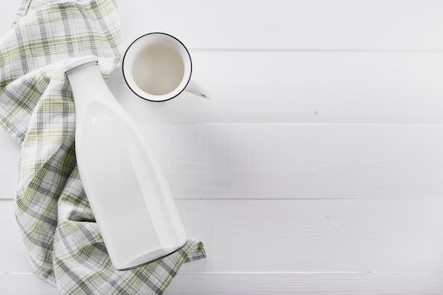 Flat lay milk bottle with cup on table