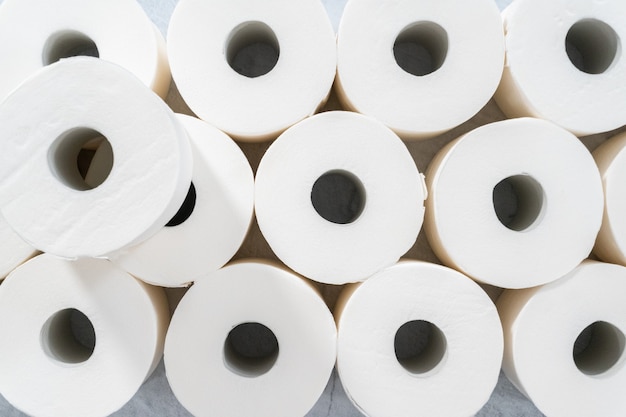 Flat lay. New white toilet paper rolls on a gray background.