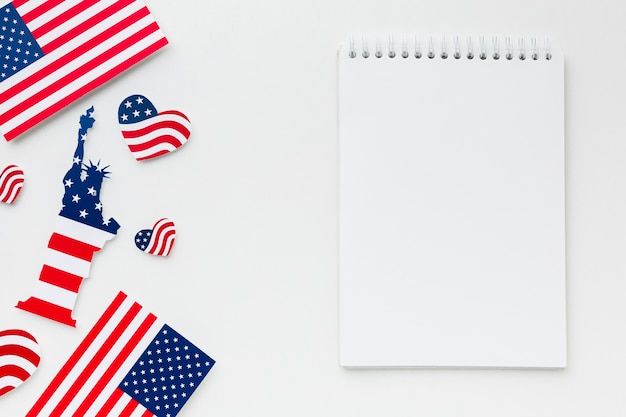 Flat lay of notebook with american flags and statue of liberty