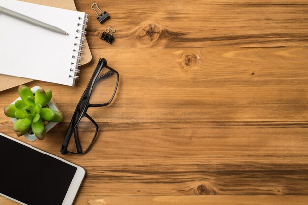 Flat lay above overhead close up view photo of digital gadget with empty touch screen eyewear open spiral notebook binder clips on light loft backdrop