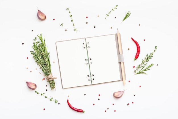 Flat lay overhead view blank notebook pages mockup text space invitation card on white background with greens herbs and spices. Menu or recipe book or food blog design with cooking ingredients