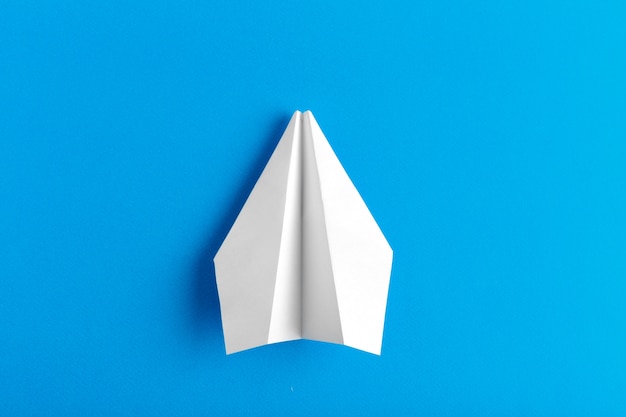 Flat lay of a paper plane on pastel blue color background