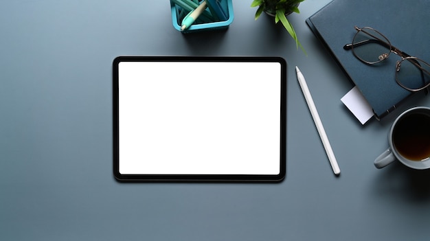 Flat lay photo of mock up digital tablet with empty screen on gray table. Blank screen for text message or information content.