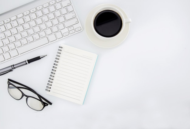 Flat lay photo of office desk with keyboard, notebook, tablet, smartphone and coffee cup