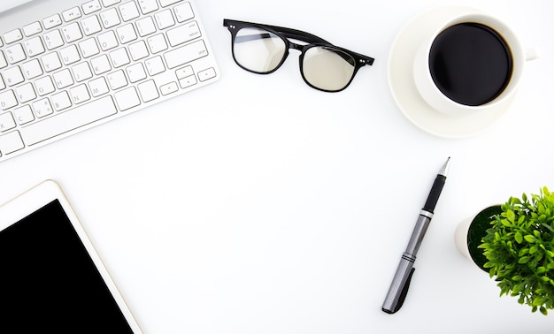 Flat lay photo of office desk with keyboard, notebook, tablet, smartphone and red cup, top view