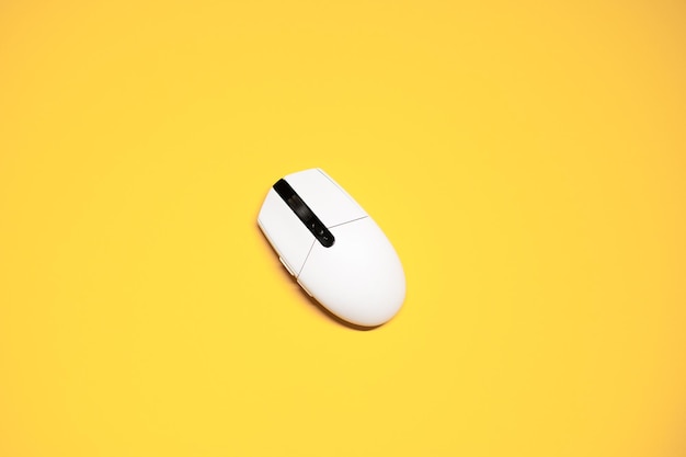 Flat lay photo of a white plastic computer mouse on an isolated yellow background