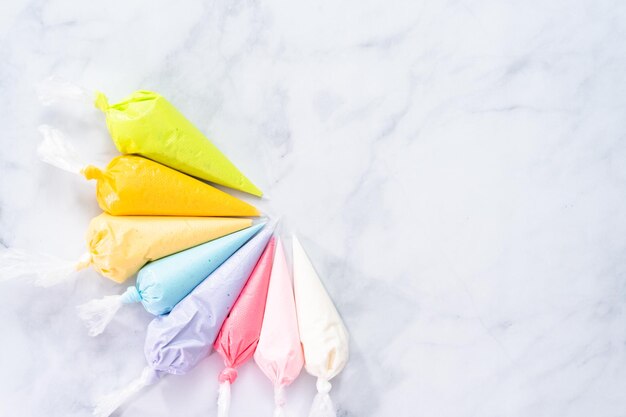 Flat lay. Piping bags with pastel color royal icing to decorate Easter sugar cookies.