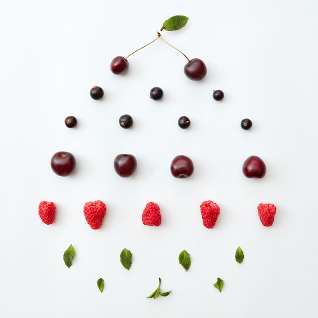 Flat lay of raspberry, cherry, black currant and green leaves of mint isolated