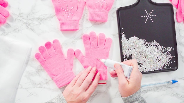 Flat lay. Rhinestone pink kids gloves with snowflake shapes.