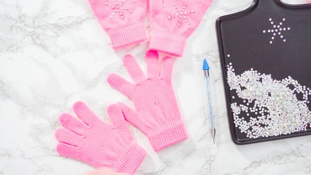 Flat lay. Rhinestone pink kids gloves with snowflake shapes.