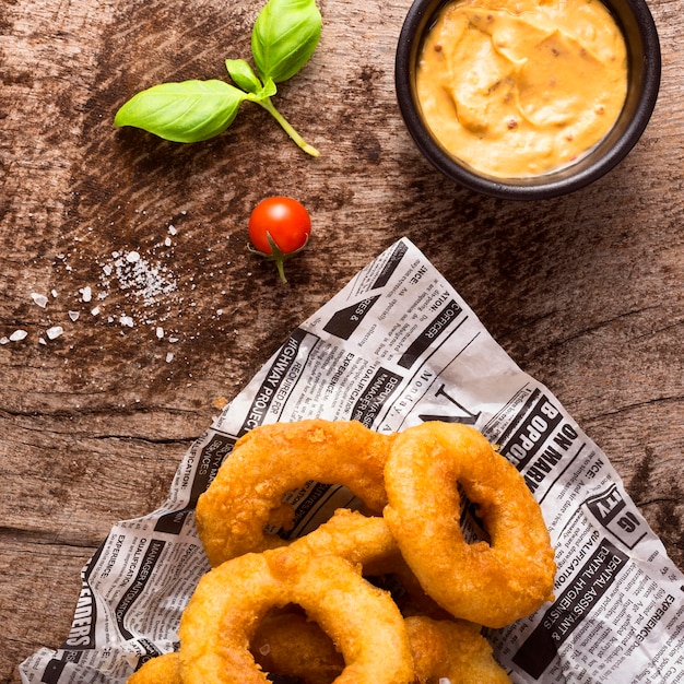 Flat lay of ring fries on newspaper with mustard