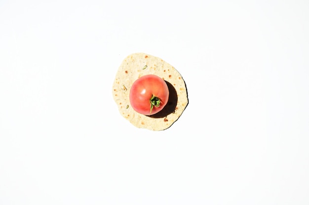 Flat lay of ripe juicy tomato on a freshly baked homemade chapati pita bread flatbread isolated over white background