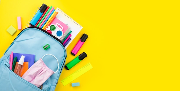 Flat lay of school essentials with backpack and colored pencils