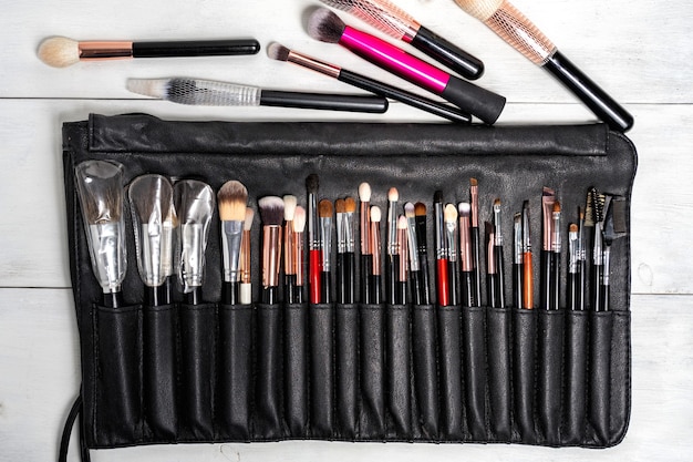 flat lay set of black makeup brushes in a black leather case.