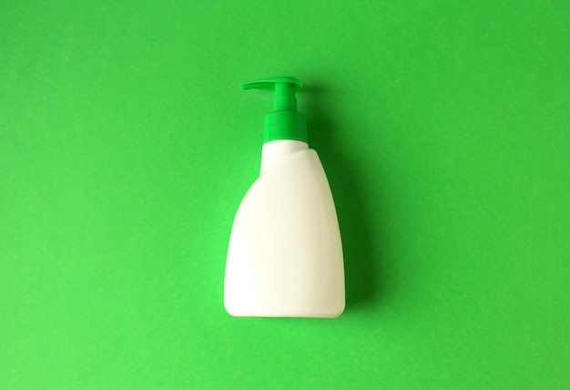 Flat lay of single bottle of liquid soap on a green surface