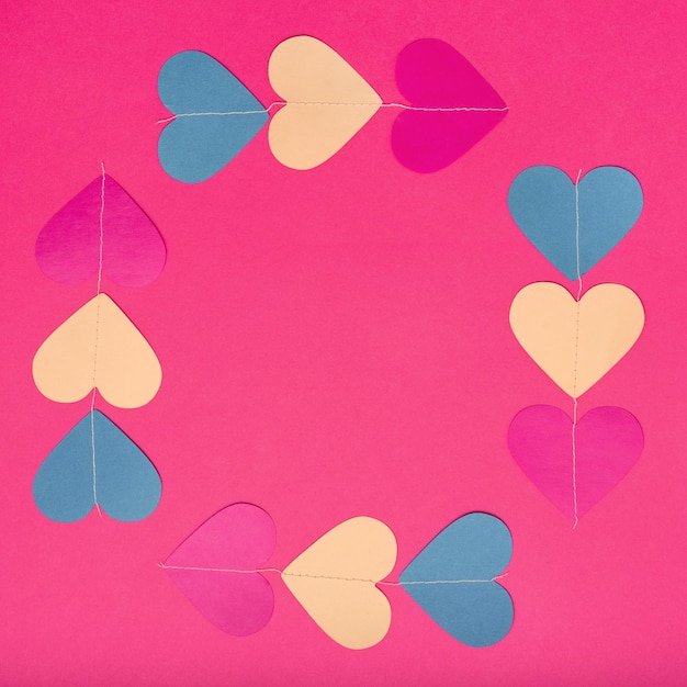 Flat lay of six colorful paper hearts on red background