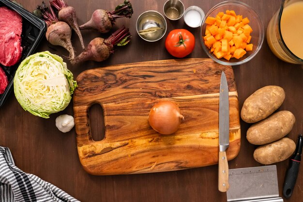 Flat lay. Slicing yellow onion on wood cutting board.