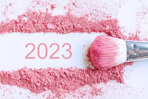 Flat lay of smear of crushed pink blush on as sample of cosmetics product with 2023 number copy space top view Happy new year conceptx9