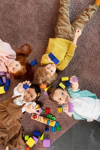 Flat lay smiley kids laying together on floor