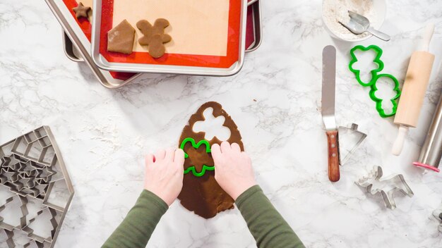 Flat lay. Step by step. Cutting out shapes with Christmas cookies cutter from gingerbread cookie dough.