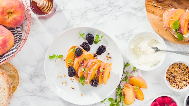 Flat lay. Step by step. Making ricotta toasts with organic peaches and berries.