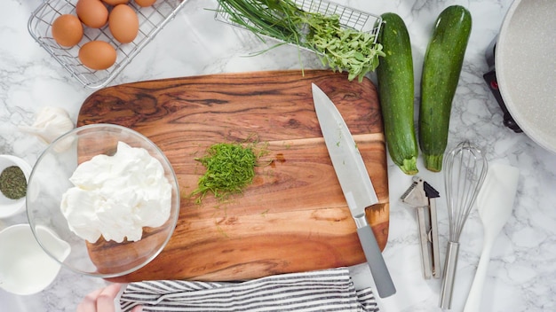 Flat lay. Step by step. Mixing fresh herbs and sour cream to make herb sour cream.