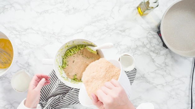 Flat lay. Step by step. Mixing ingredients in a mixing bowl to make zucchini cakes.