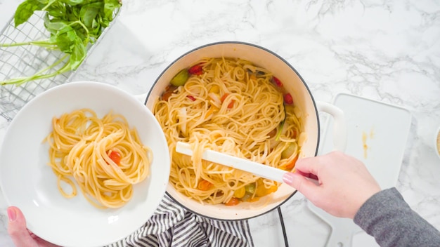 Flat lay. Step by step. Serving a one-pot pasta into a white pasta plate.