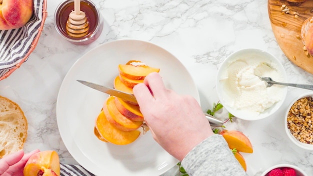 Flat lay. Step by step. Slicing organic peach to make a ricotta and peach toast on ciabatta bread.