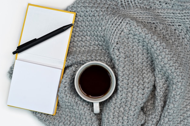 Flat lay of sweater with coffee and notepad