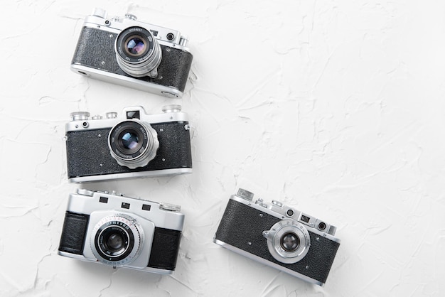 Flat lay of three old vintage photo cameras on the white background with free space for text mock up