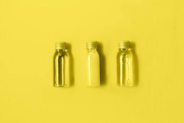 Photo flat lay of three small mockup bottles with spa cosmetic products in trendy yellow color