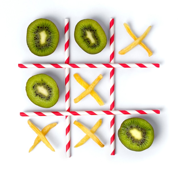 Flat lay Tic tac toe made of kiwi, fries and straws.