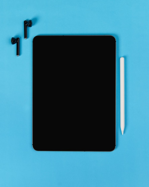 Flat lay top view blank screen digital tablet on blue background home office workspace