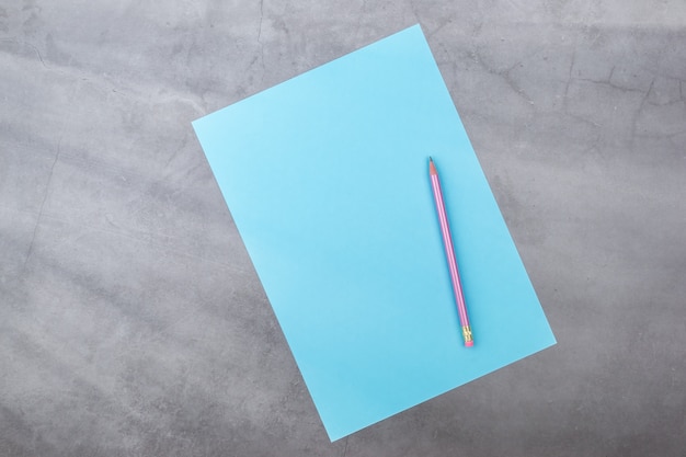 Flat lay, top view, blue sheet and pencil on a gray textured background