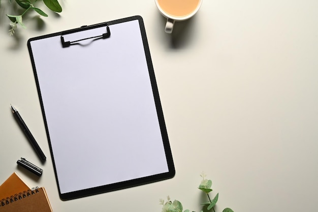 Flat lay top view clipboard with blank paper pen coffee cup and eucalyptus branches on white background