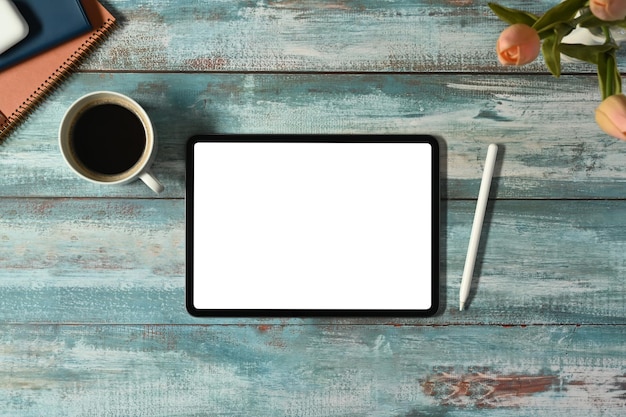 Flat lay top view of digital tablet with white screen coffee cup and books on rustic wooden table