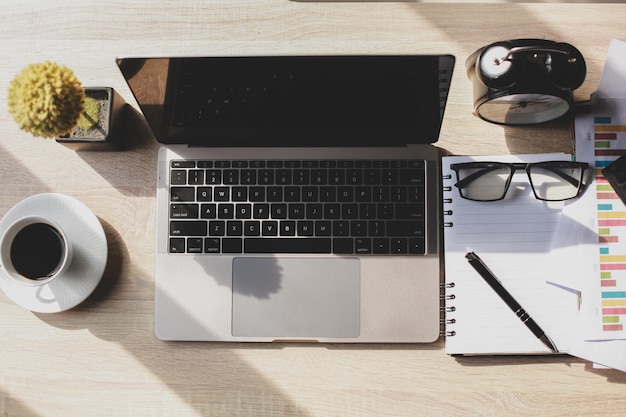 Flat lay top view of glasses and pen on the book with A cup of coffee laptop alarm clock and decor