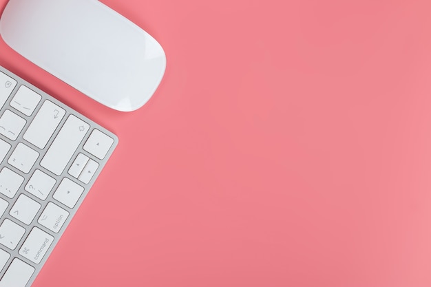 Flat lay, top view office table desk. Workspace with keyboard and mouse on pink background