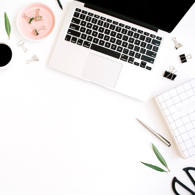 Flat lay, top view office table desk. Workspace with notebook, laptop, palm branch, coffee cup, scissors and clips on white background.