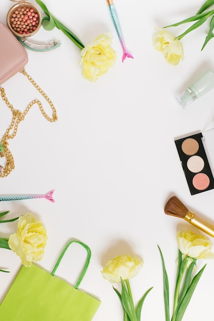 Flat lay top view table desk frame Feminine blogger desk workspace with cosmetics lipstick and tulip flowers on white background