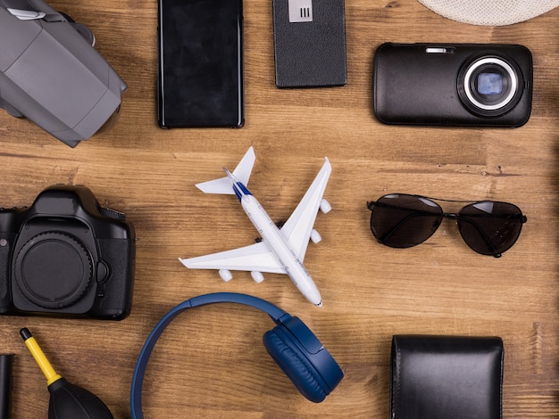 Flat lay top view of traveler photographer accessories on wooden table. Hat. Drone. Headphones. Camera. Wallet.